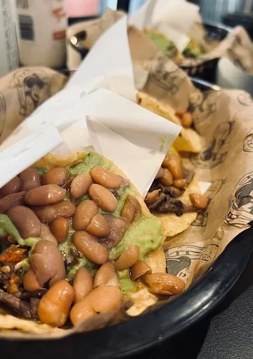 Taco dish at Tijuanazo Hipodromo, featuring beans and guacamole on a base of meat.