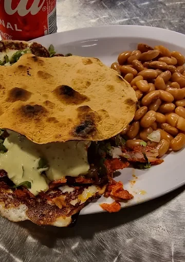 Tostada dish at Tijuanazo Hipodromo, served with seasoned meat, toppings, and a side of beans.