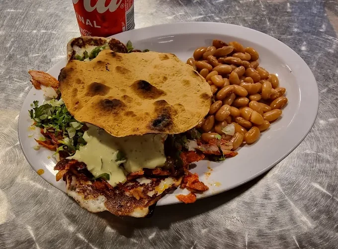 Tostada dish at Tijuanazo Hipodromo, served with seasoned meat, toppings, and a side of beans.