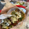 A basket of flavorful tacos at Tijuanazo Hipodromo, topped with green sauce, cilantro, and onions.