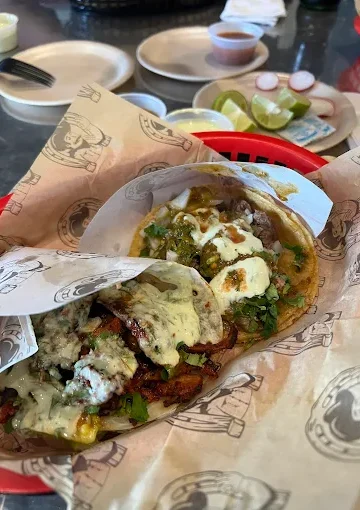 A basket of flavorful tacos at Tijuanazo Hipodromo, topped with green sauce, cilantro, and onions.