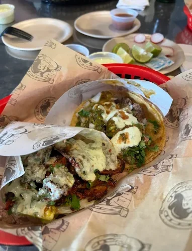 A basket of flavorful tacos at Tijuanazo Hipodromo, topped with green sauce, cilantro, and onions.