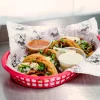 Taco platter at Tijuanazo Hipodromo, featuring four tacos and two dipping sauces.
