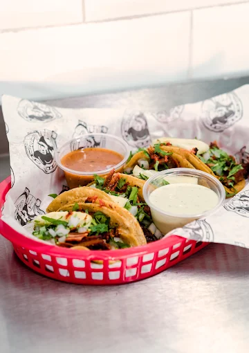 Taco platter at Tijuanazo Hipodromo, featuring four tacos and two dipping sauces.