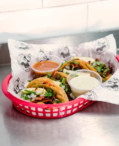 Taco platter at Tijuanazo Hipodromo, featuring four tacos and two dipping sauces.