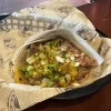 A taco at Tijuanazo Hipodromo, featuring tender meat, onions, cilantro, and green salsa.