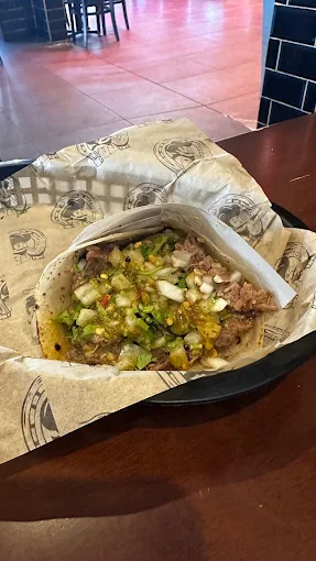 A taco at Tijuanazo Hipodromo, featuring tender meat, onions, cilantro, and green salsa.
