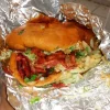 A delicious sandwich at Tijuanazo Hipodromo, loaded with seasoned meat, vegetables, and creamy sauce.