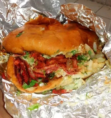 A delicious sandwich at Tijuanazo Hipodromo, loaded with seasoned meat, vegetables, and creamy sauce.