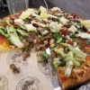 Tasty pizza with various toppings at Tijuanazo Hipodromo, featuring meats and pineapple.
