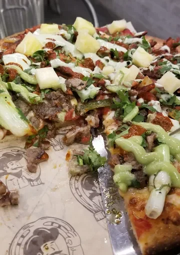 Tasty pizza with various toppings at Tijuanazo Hipodromo, featuring meats and pineapple.