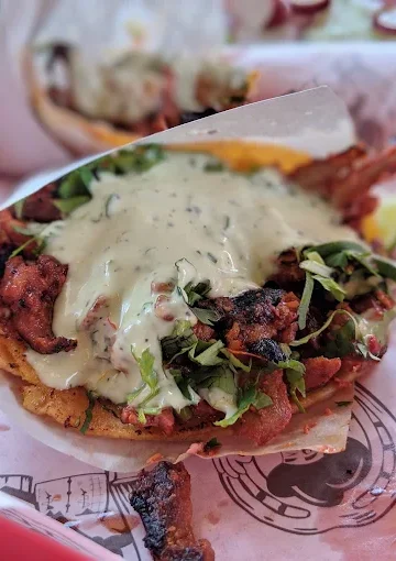A flavorful taco at Tijuanazo Hipodromo, topped with grilled meat, cilantro, and creamy green sauce.