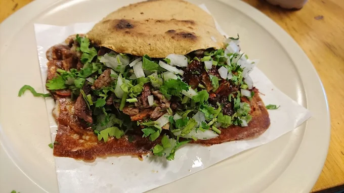 A crispy taco at Tijuanazo Hipodromo, loaded with meat, cilantro, and onions.